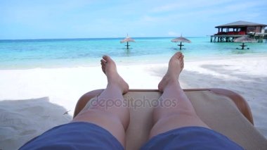 Tropikal okyanus cennete turist bacakları çıplak ayak altın kum plaj bankta oturan işaret