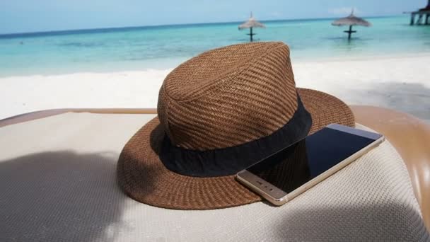 Telefone inteligente com chapéu de palha no mar das Maldivas. Férias relaxar fundo abstrato — Vídeo de Stock