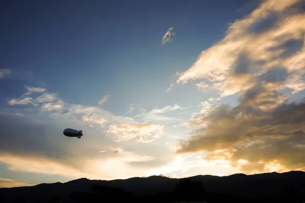 Helium blimp advertising ballon floating sunset sky and mountain — Stock Photo, Image