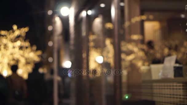 La lumière de Noël de l'arbre illumine la vitrine et le verre du restaurant. Les gens traînent en vacances spéciales — Video