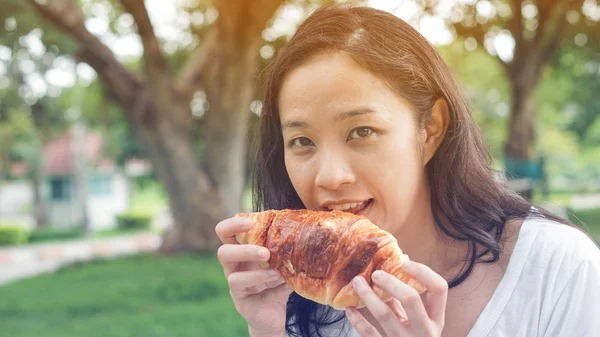 아시아 여자 들고와 녹색 찾기에 신선한 구운된 베이커리를 먹는 — 스톡 사진