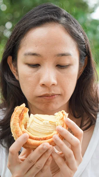 Азіатський жінка тримає і їдять свіжі випікається хлібобулочної в зелений захованих — стокове фото