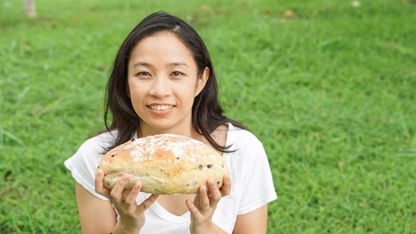 Asian woman holding and eating fresh baked bakery in green backg — Stock Photo, Image
