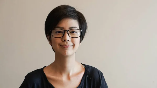 Asijské žena s krátkými vlasy a brýle na barvu pozadí — Stock fotografie
