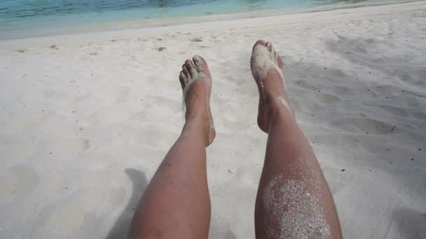 Pies relajados jugando con arena blanca en la isla tropical. POV sentado en el asiento de la playa — Vídeos de Stock