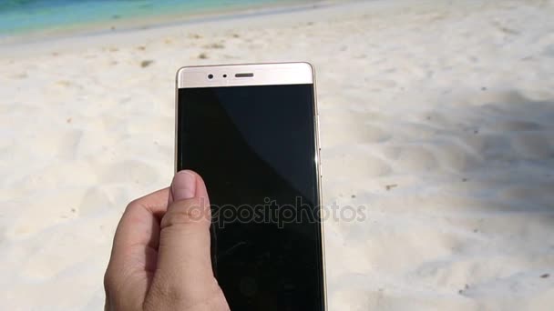 Использовать смартфон на пляже Голубого океана в отпуске. POV рука и море замедленного движения — стоковое видео