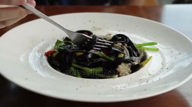 Siyah mürekkep balığı spagetti yemek için çatal kullanarak makarna yemek mürekkep 