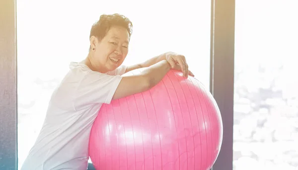 Asiatico anziano sano vecchio donna esercizio con rosa ginnastica palla — Foto Stock