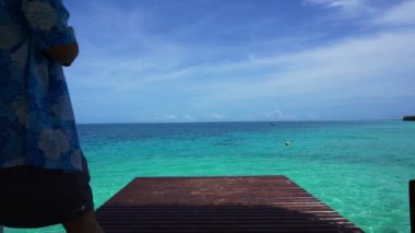 Ahşap güverte oturan kişi huzurlu ve sakin bir deniz ve güzel gökyüzü sakin ol