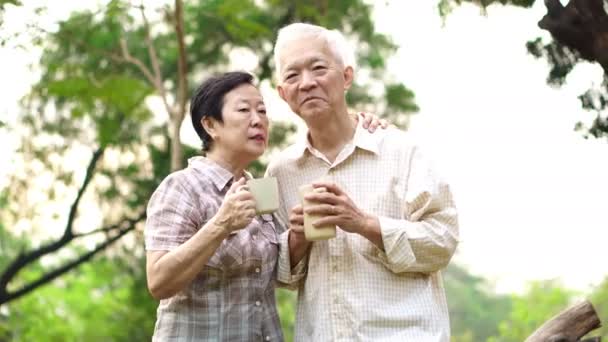 Glad gammal asiatiska senior par dating på park på morgonen. Kaffe konversation — Stockvideo