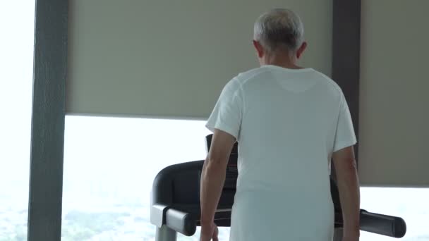 Asiatischer Senior läuft auf einem Laufband im Fitnessstudio gesunde Lebensstilübung — Stockvideo