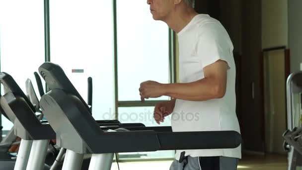 Asijské starší muž běží na běžeckém pásu v posilovně cvičení zdravého životního stylu — Stock video