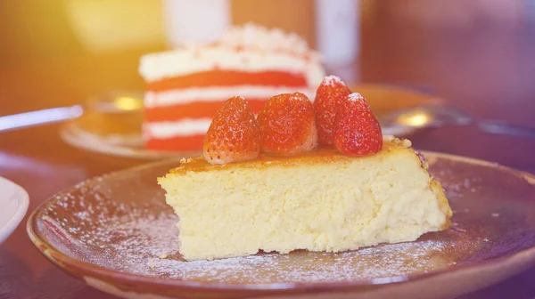 Кусок чизкейка с клубничным и красным бархатным тортом в пекарне — стоковое фото