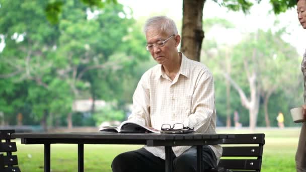 Asiatiska senior par dricka kaffe i morgon vacker park — Stockvideo