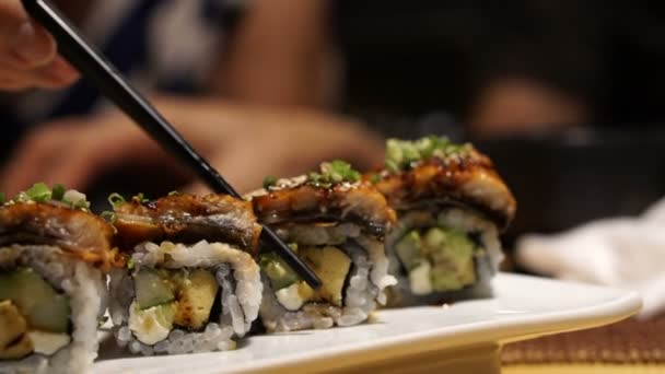 Hand mit Essstäbchen Aal Avocado mit Käse-Sushi-Rolle pflücken — Stockvideo