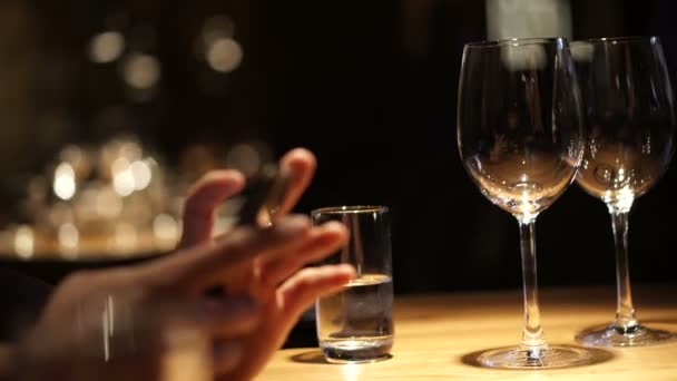 Χέρι χρησιμοποιώντας smartphone σε πολυτελές εστιατόριο με ποτήρια κρασιού — Αρχείο Βίντεο