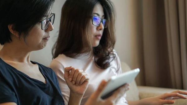 Twee Aziatische vrienden kijken ding op tablet en computer delen — Stockfoto