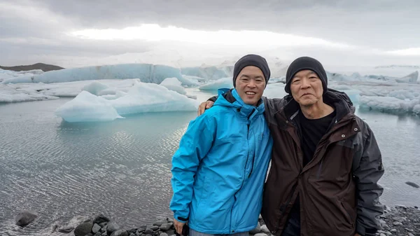 Сын-азиат везет отца в Исландию, чтобы увидеть лагуну ледников. — стоковое фото