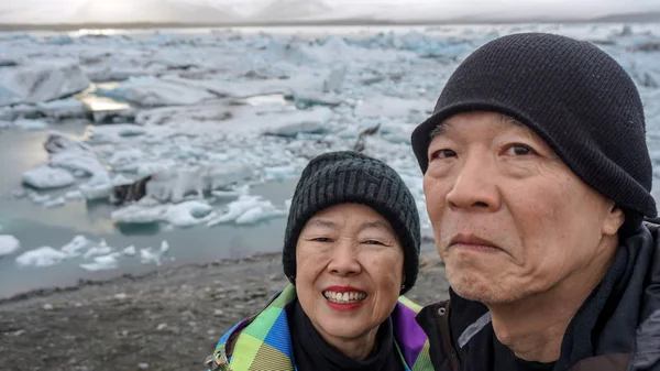 Asiático casal sênior diversão viagem na Islândia, majestoso glaciar lagoa — Fotografia de Stock