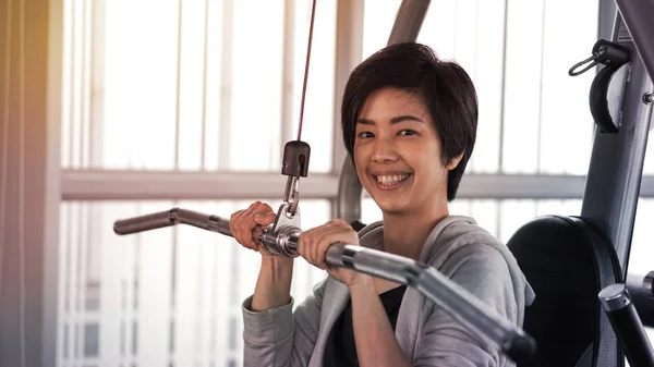 Asiático cabelo curto mulher fitness máquina de treinamento sorriso rosto — Fotografia de Stock