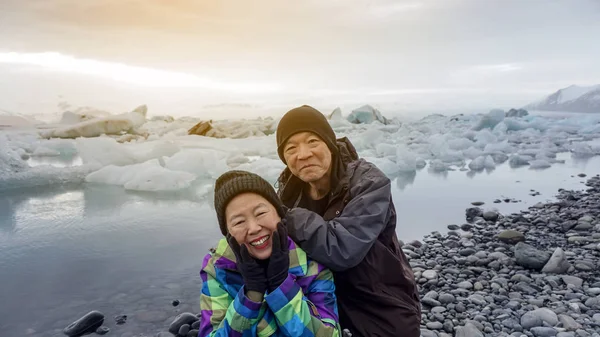 Ασιατισα Ζευγάρι ανώτερος διασκεδαστικό ταξίδι στην Ισλανδία, επιβλητικό παγετώνα λιμνοθάλασσα — Φωτογραφία Αρχείου