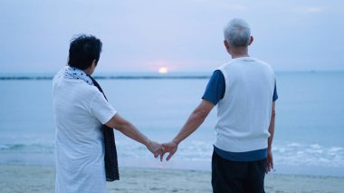 Asya kıdemli çift gündoğumu denizde