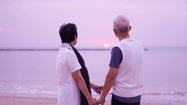 Asian senior couple dating at sunrise sea — Stock Photo, Image