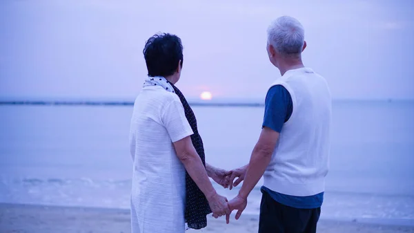 Asian senior couple dating at sunrise sea — Stock Photo, Image