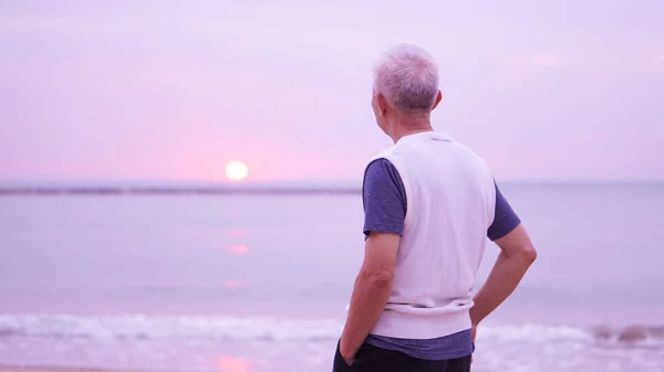 Asian senior man standing alone at sunrise morning copy space — Stock Photo, Image