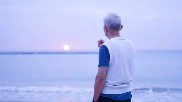 Asian senior man standing alone at sunrise morning copy space — Stock Photo, Image