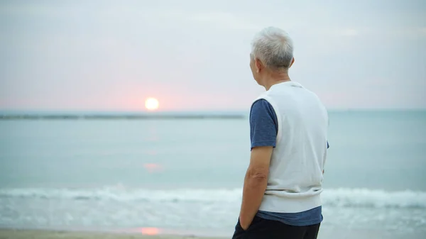 Asian senior man standing alone at sunrise morning copy space — Stock Photo, Image