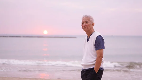 Asiatischer Senior, der allein am Morgen des Sonnenaufgangs steht — Stockfoto