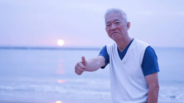 Asian senior man thumbs up at sunrise financial worry free