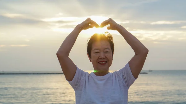 Ανώτερος γυναίκα της Ασίας με το χέρι εκμετάλλευση ήλιο έννοια της επιτυχίας και — Φωτογραφία Αρχείου