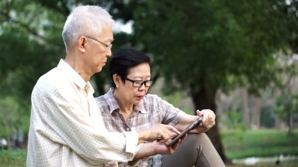 Asiático Senior Pareja Usando Tableta Juntos Parque — Vídeo de stock