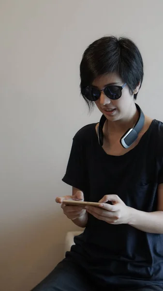 Asiatisk kvinna livsstil med hjälp av smartphone när du använder hörlurarna ett — Stockfoto