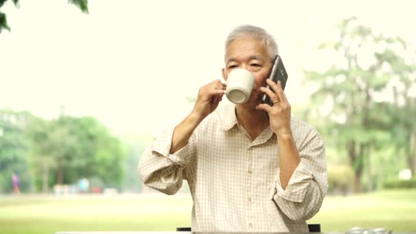 Aziatische Senior Gebruik Telefoon Terwijl Drinken Koffie Park Ochtend Business — Stockvideo