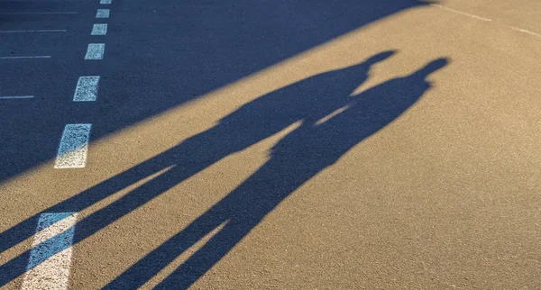 Couple long shadow holding hand on road trip Stock Photo