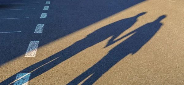 Couple long shadow holding hand on road trip Royalty Free Stock Images