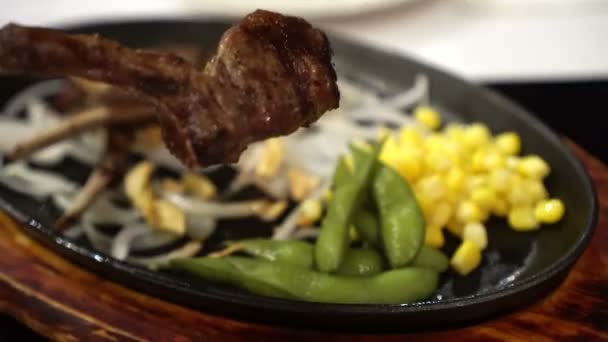 Hand Holding Eating Rack Lamb Steak Hot Pan — Stock Video