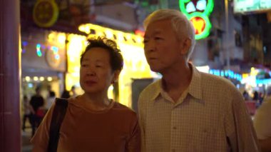 Asyalı yaşlı çift Hong Kong sokaklarında mutlu mesut yürüyor.