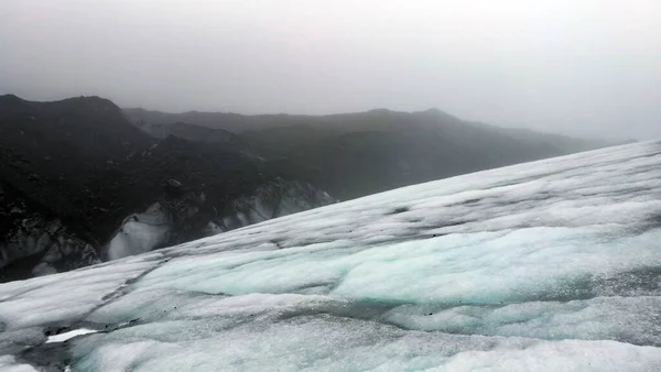 Bewolkt weer gletsjer wandelen in IJsland vulkanische zwarte steen — Stockfoto