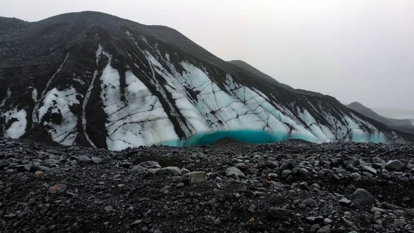 Bewolkt weer gletsjer wandelen in IJsland vulkanische zwarte steen — Stockfoto