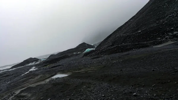 Bewolkt weer gletsjer wandelen in IJsland vulkanische zwarte steen — Stockfoto