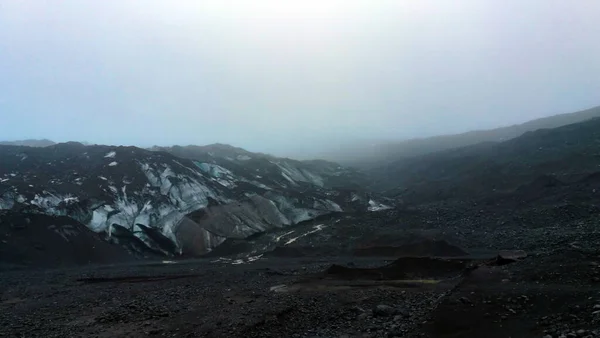 Bewolkt weer gletsjer wandelen in IJsland vulkanische zwarte steen — Stockfoto