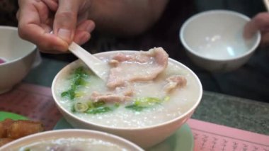 Eller Hong Kong Çin usulü congee bolves ve hamur çubukları yiyor.
