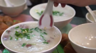 Eller Hong Kong Çin usulü congee bolves ve hamur çubukları yiyor.