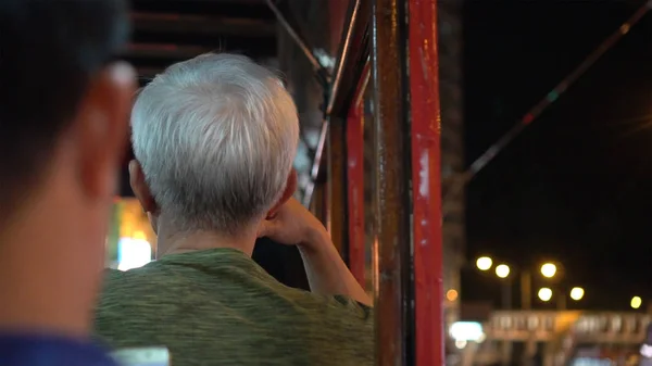 Азиатский пожилой человек, сидящий в гонконгском трамвае, думает — стоковое фото
