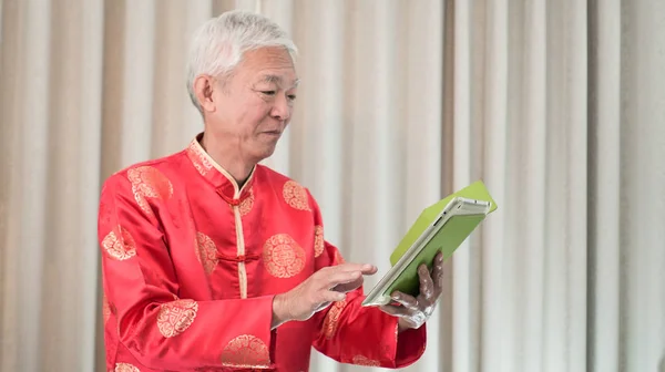 Asiático homem sênior segurando tablet no feriado de Ano Novo Chinês — Fotografia de Stock