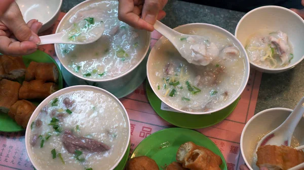 Las manos comiendo arroz congee hervir y masa frita Hong Kong Cantones — Foto de Stock